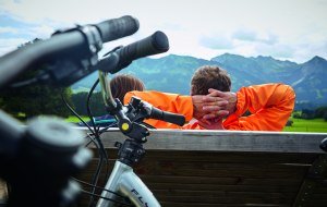 Radfahrer machen an der Radrunde Allgäu Pause und blicken auf die Allgäuer Alpen. © Allgäu GmbH